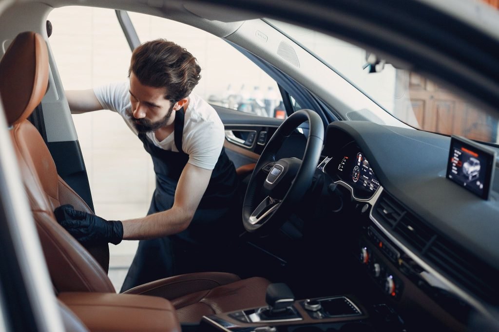 A man details the passenger seat of a car
