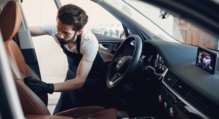 A man applies ceramic coating on the door panel of a car